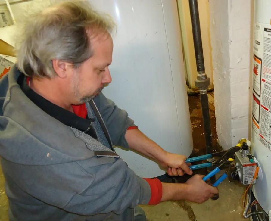 A plumber tightening a pipe fitting with two wrenches