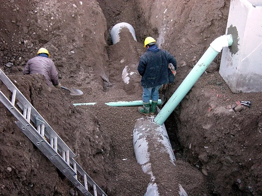 Workers laying pipe in an open trench